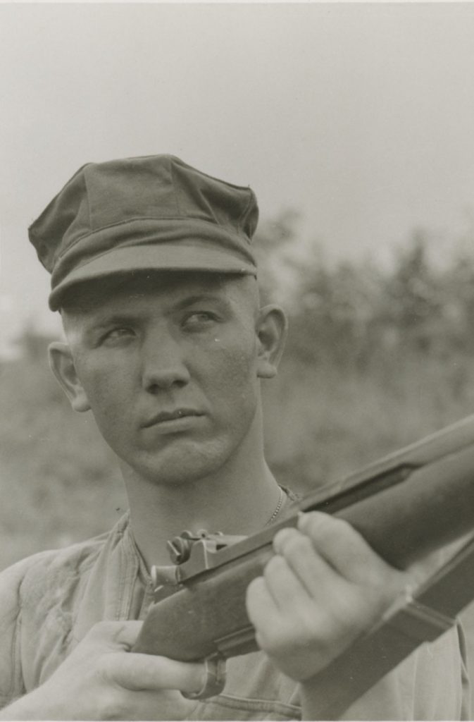 Peter Lev wearing a hat and holding a rifle